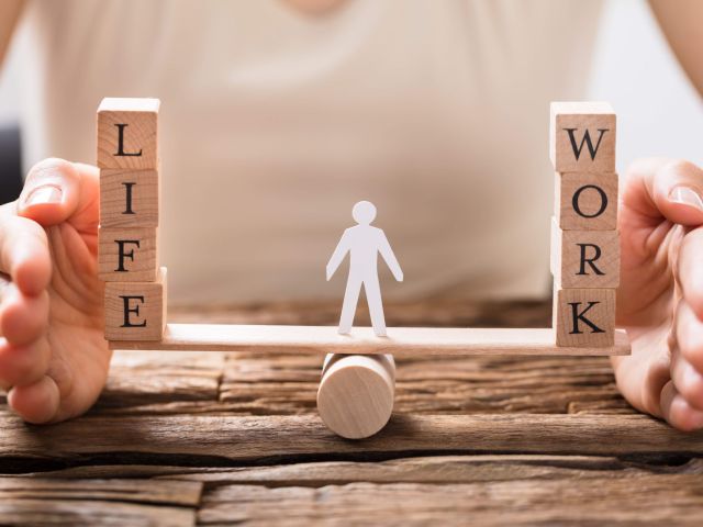 Close-up Of A Human Hand Protecting Balance Between Life And Work On Seesaw